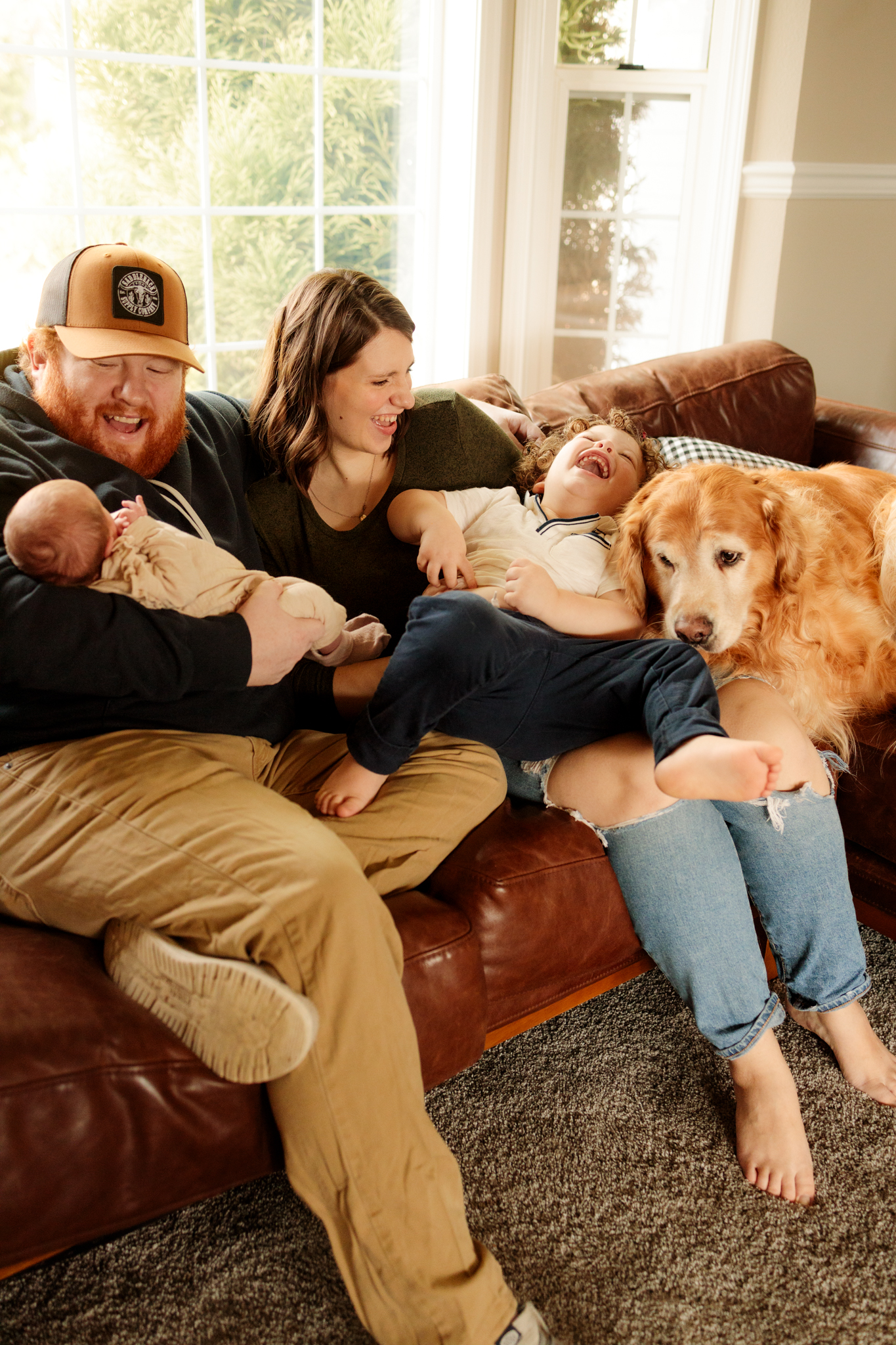 lifestyle newborn photo of family snuggling on the couch with their golden retriever in tacoma, wa